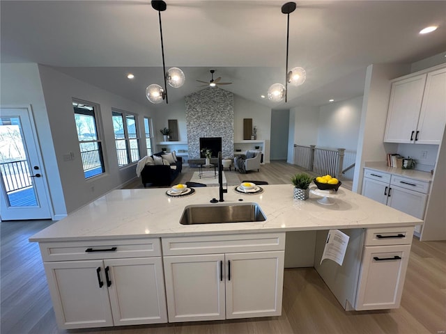 kitchen featuring a wealth of natural light, a center island with sink, a sink, open floor plan, and white cabinets