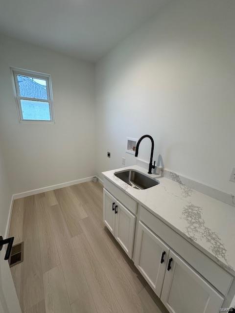 laundry area with baseboards, light wood-style flooring, electric dryer hookup, washer hookup, and a sink