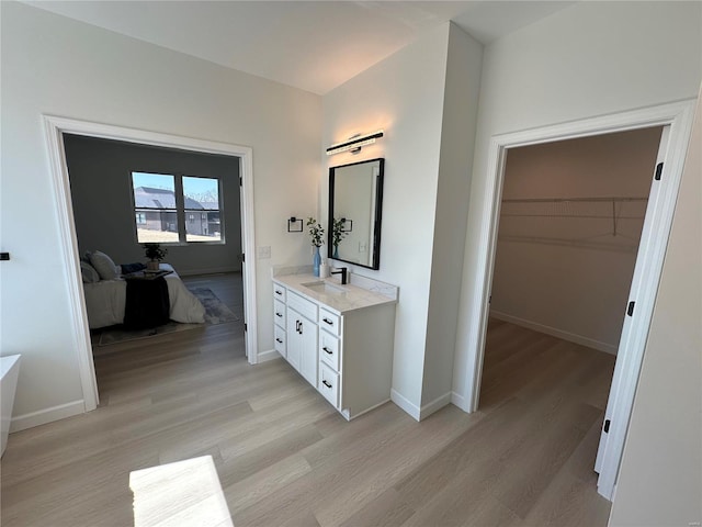 bathroom with connected bathroom, baseboards, wood finished floors, and vanity