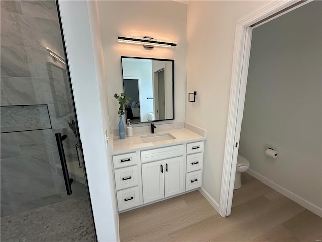 full bathroom featuring vanity, wood finished floors, baseboards, a stall shower, and toilet