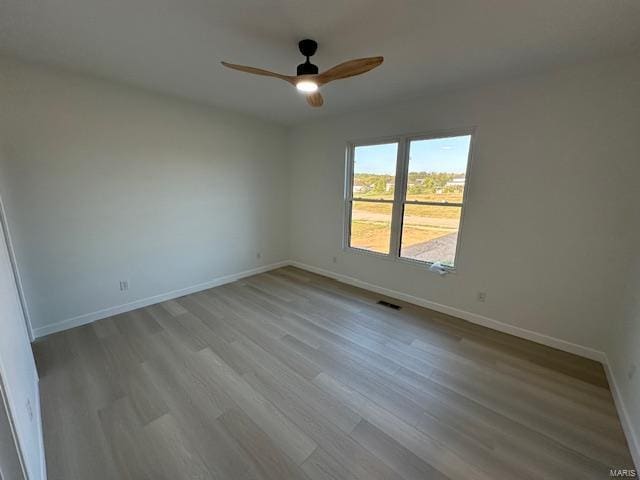 spare room featuring ceiling fan, baseboards, and wood finished floors