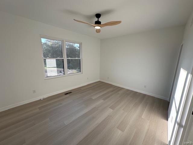 unfurnished room with visible vents, ceiling fan, baseboards, and wood finished floors