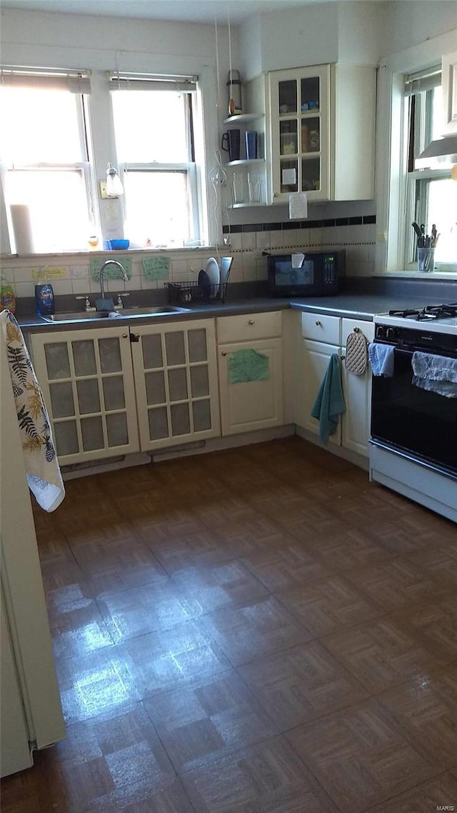 kitchen featuring tasteful backsplash, white cabinets, sink, and white range with gas stovetop