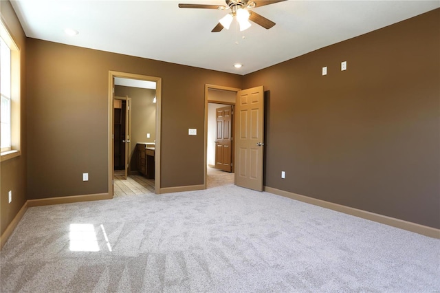 unfurnished bedroom featuring light colored carpet, ceiling fan, and ensuite bathroom