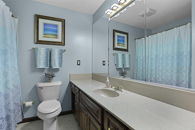 bathroom featuring toilet, vanity, a textured ceiling, and tile patterned floors