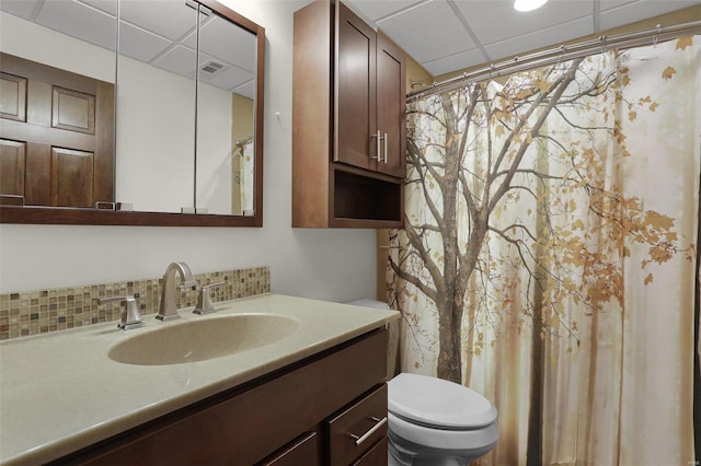 bathroom featuring vanity, toilet, and a drop ceiling