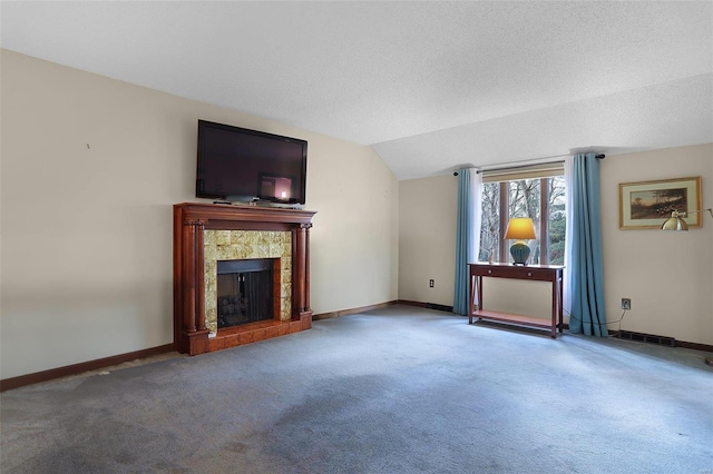 unfurnished living room featuring carpet flooring, lofted ceiling, a fireplace, and a textured ceiling