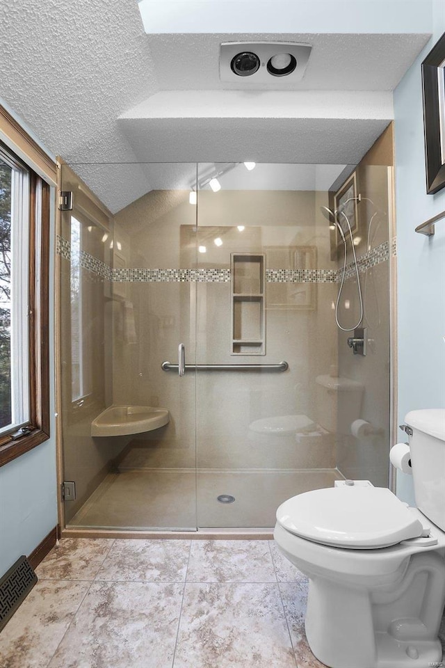 bathroom featuring a textured ceiling, toilet, walk in shower, and tile patterned floors