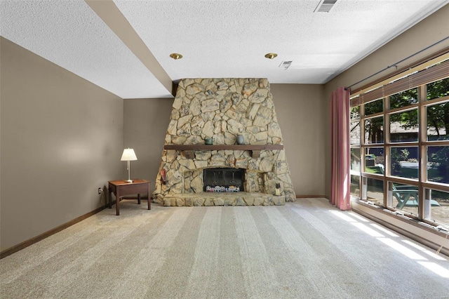 unfurnished living room featuring a stone fireplace, carpet floors, and a textured ceiling