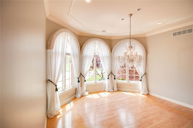 empty room featuring a chandelier, hardwood / wood-style flooring, and ornamental molding