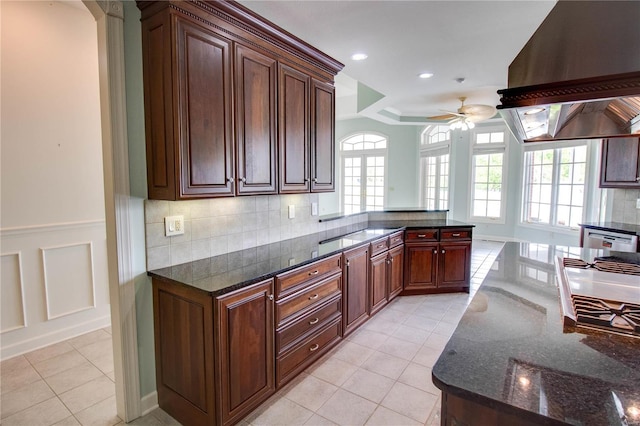 kitchen featuring backsplash, dark stone countertops, custom exhaust hood, and light tile floors