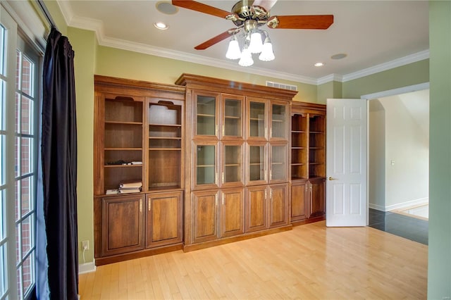 interior space featuring a wealth of natural light, ceiling fan, crown molding, and light wood-type flooring