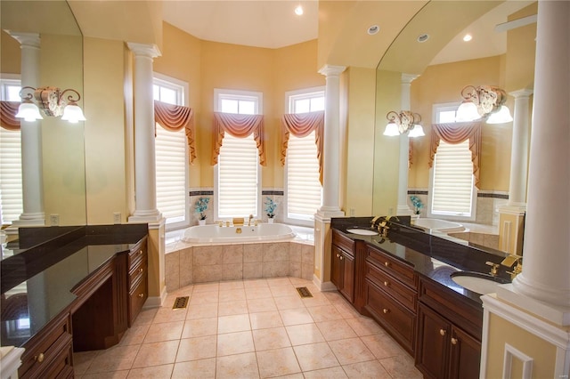 bathroom featuring ornate columns, tile flooring, tiled tub, and vanity