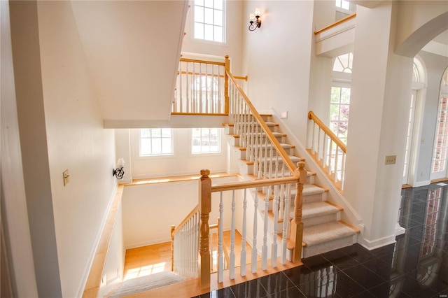 staircase with tile floors and a towering ceiling