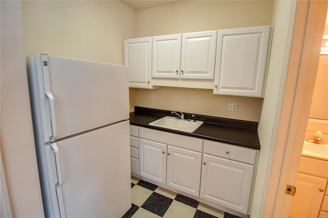 kitchen featuring white cabinets, sink, white fridge, and light tile floors