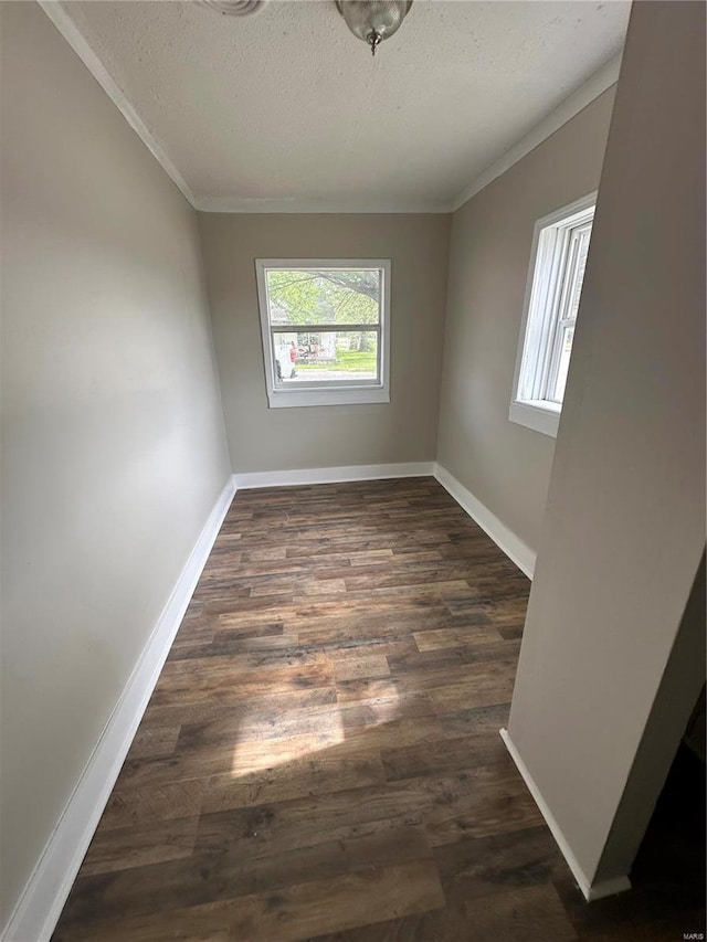 empty room featuring ornamental molding, dark hardwood / wood-style flooring, and a textured ceiling