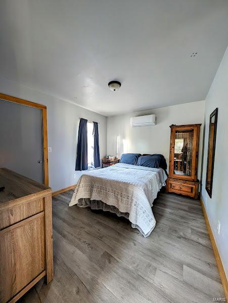 bedroom with dark wood-type flooring and a wall mounted AC