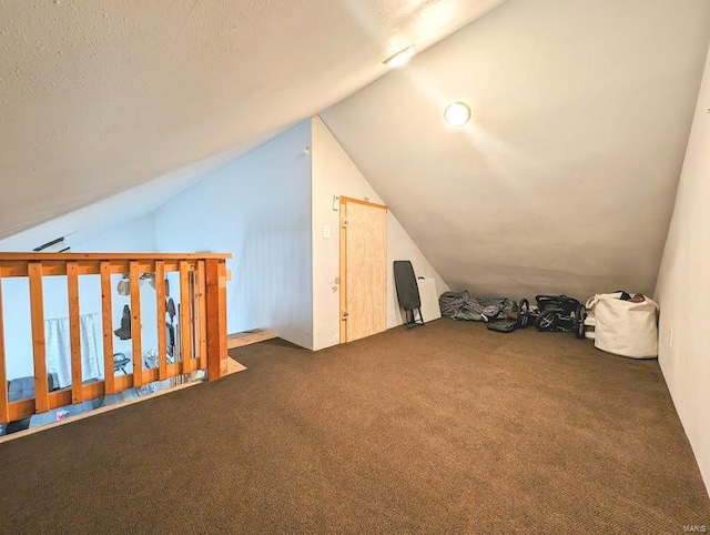 bonus room with dark colored carpet and vaulted ceiling