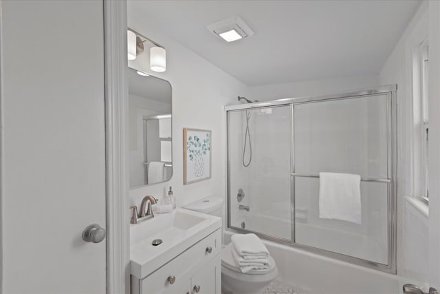 full bathroom with bath / shower combo with glass door, vanity, and toilet