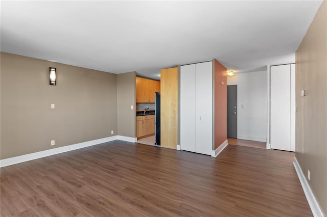 unfurnished living room featuring sink and dark hardwood / wood-style flooring