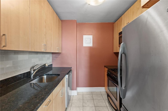 kitchen featuring appliances with stainless steel finishes, sink, light tile patterned floors, dark stone countertops, and decorative backsplash