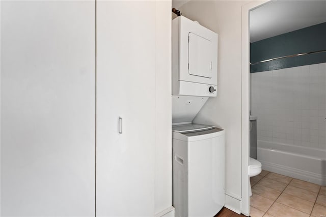 washroom featuring stacked washer and clothes dryer and light tile patterned floors