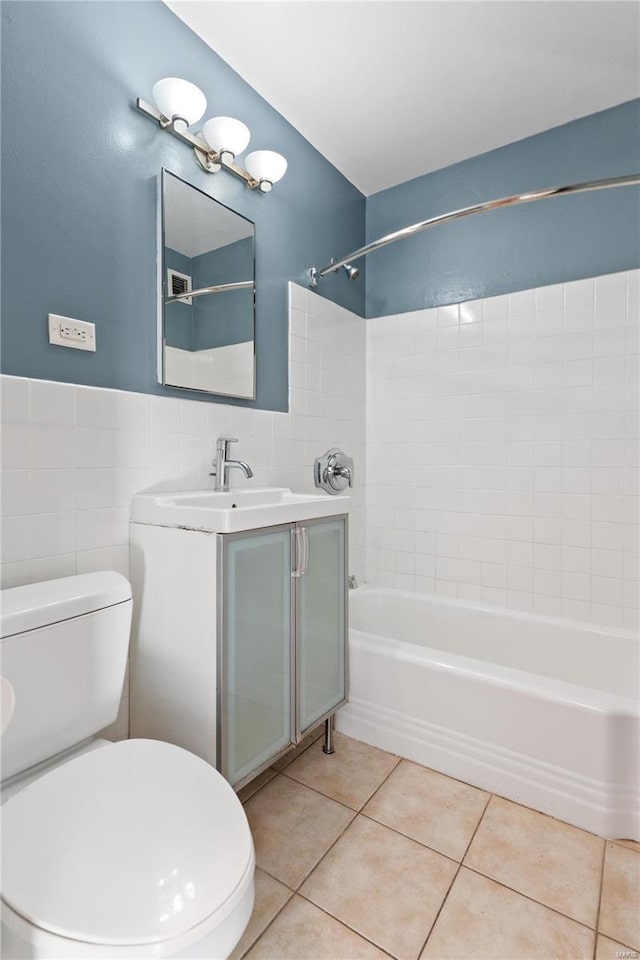 full bathroom with tile patterned floors, tile walls, tiled shower / bath combo, toilet, and vanity