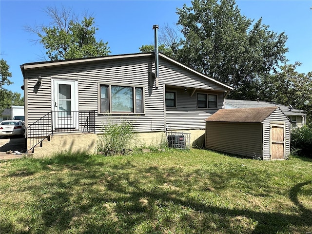 back of property with central AC unit, a lawn, and a storage unit