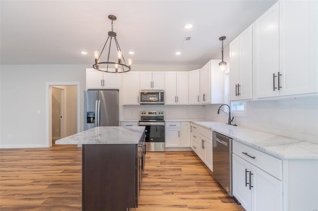 kitchen with sink, a notable chandelier, a kitchen island, light hardwood / wood-style flooring, and appliances with stainless steel finishes