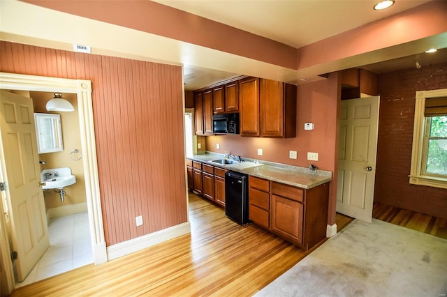 kitchen with light stone countertops, sink, black appliances, and light wood-type flooring