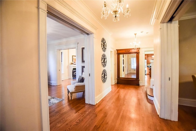 corridor with hardwood / wood-style flooring, ornamental molding, and a chandelier