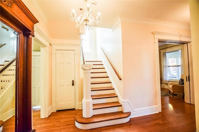 staircase with a chandelier, wood-type flooring, and crown molding