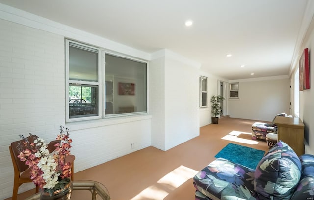 living room featuring carpet, ornamental molding, and brick wall