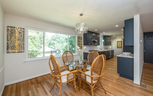 dining area featuring light hardwood / wood-style flooring, plenty of natural light, a notable chandelier, and sink