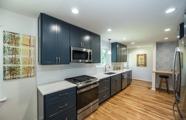 kitchen with sink, hanging light fixtures, stainless steel appliances, tasteful backsplash, and light hardwood / wood-style flooring