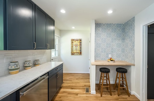 kitchen featuring dishwasher, tasteful backsplash, light stone counters, and light hardwood / wood-style floors