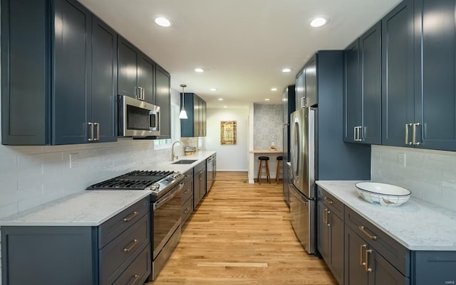 kitchen featuring light wood-type flooring, backsplash, stainless steel appliances, and sink