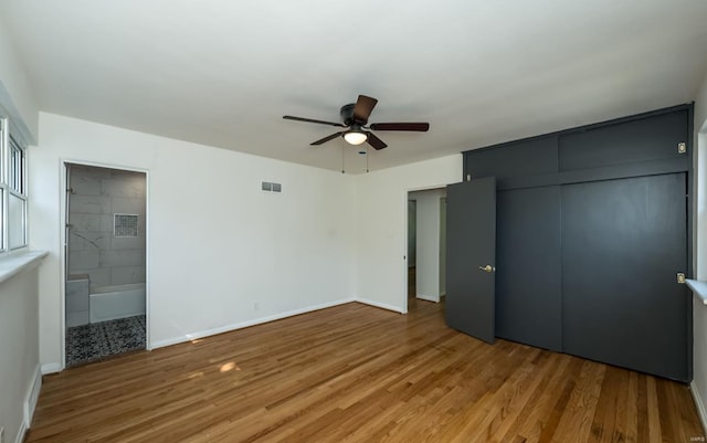 unfurnished bedroom with ceiling fan, wood-type flooring, connected bathroom, and a closet