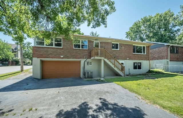 view of front of house featuring cooling unit, a front yard, and a garage