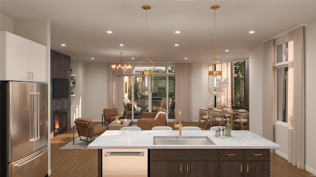 kitchen featuring dark brown cabinetry, white cabinets, stainless steel fridge, a tile fireplace, and dark hardwood / wood-style flooring