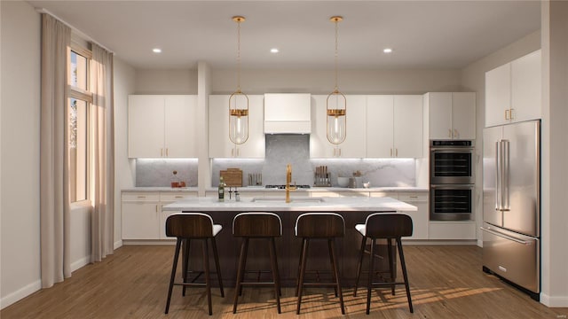 kitchen with white cabinets, a kitchen island with sink, stainless steel appliances, and dark hardwood / wood-style flooring