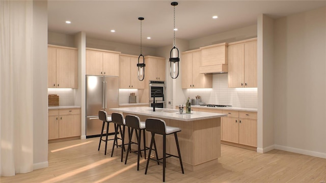 kitchen featuring appliances with stainless steel finishes, light wood-type flooring, light brown cabinets, and an island with sink