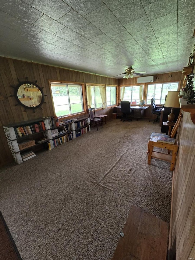 misc room featuring plenty of natural light, carpet, wooden walls, and ceiling fan