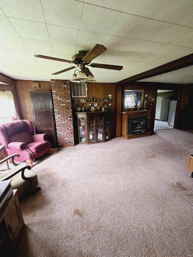 living room with carpet flooring, ceiling fan, and wooden walls