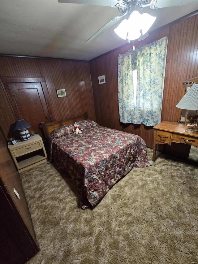 carpeted bedroom featuring ceiling fan and wooden walls