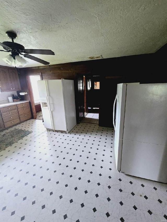 kitchen with white refrigerator with ice dispenser, white fridge, ceiling fan, and light tile floors