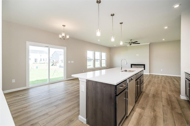 kitchen featuring dark brown cabinetry, sink, stainless steel dishwasher, an island with sink, and light wood-type flooring