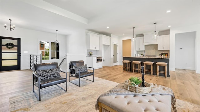 living room featuring a notable chandelier, light wood-type flooring, and sink