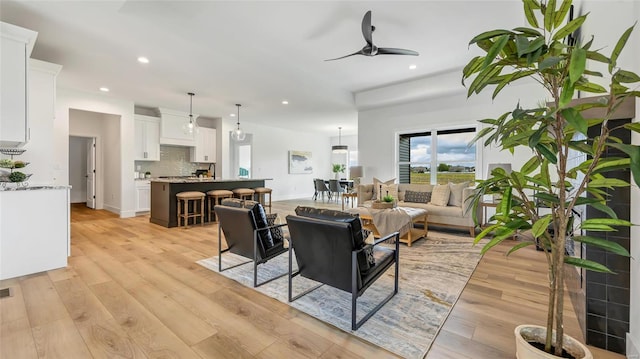 living room with ceiling fan and light hardwood / wood-style flooring