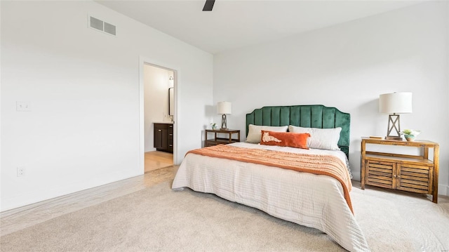 bedroom with light carpet, connected bathroom, and ceiling fan